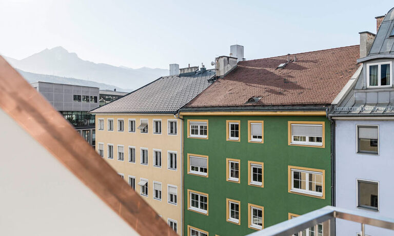 Balcony-view of Panorama Suite. You can see roofs of houses, in the background the mountain range in Innsbruck