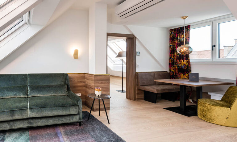 Blick vom Vorraum des Panorama Apartment 1: Tisch mit Sitzgelegenheit, Couch und Tür zum Zimmer nebenan