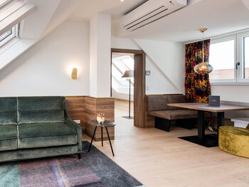 Blick vom Vorraum des Panorama Apartment 1: Tisch mit Sitzgelegenheit, Couch und Tür zum Zimmer nebenan